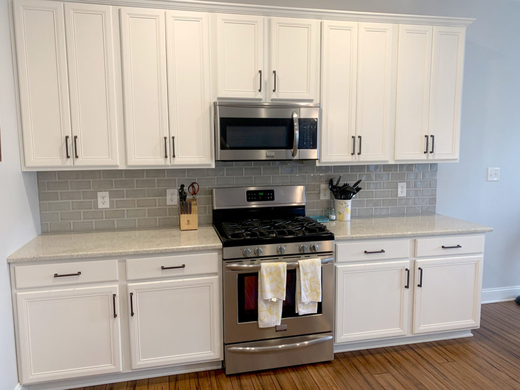 After photos of Hartley Group Coatings refinished mitered white cabinets with modern black handles.